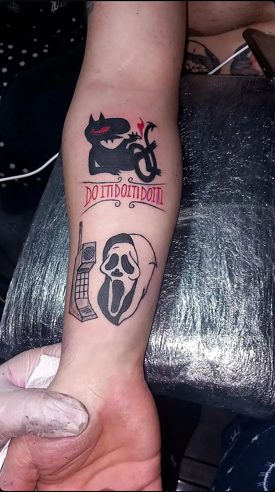 Tetovaža maske iz horora i mačke na podlaktici.